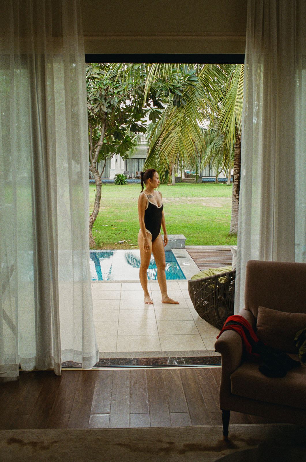 Guest standing in a villa doorway looking out to the garden, shot on film